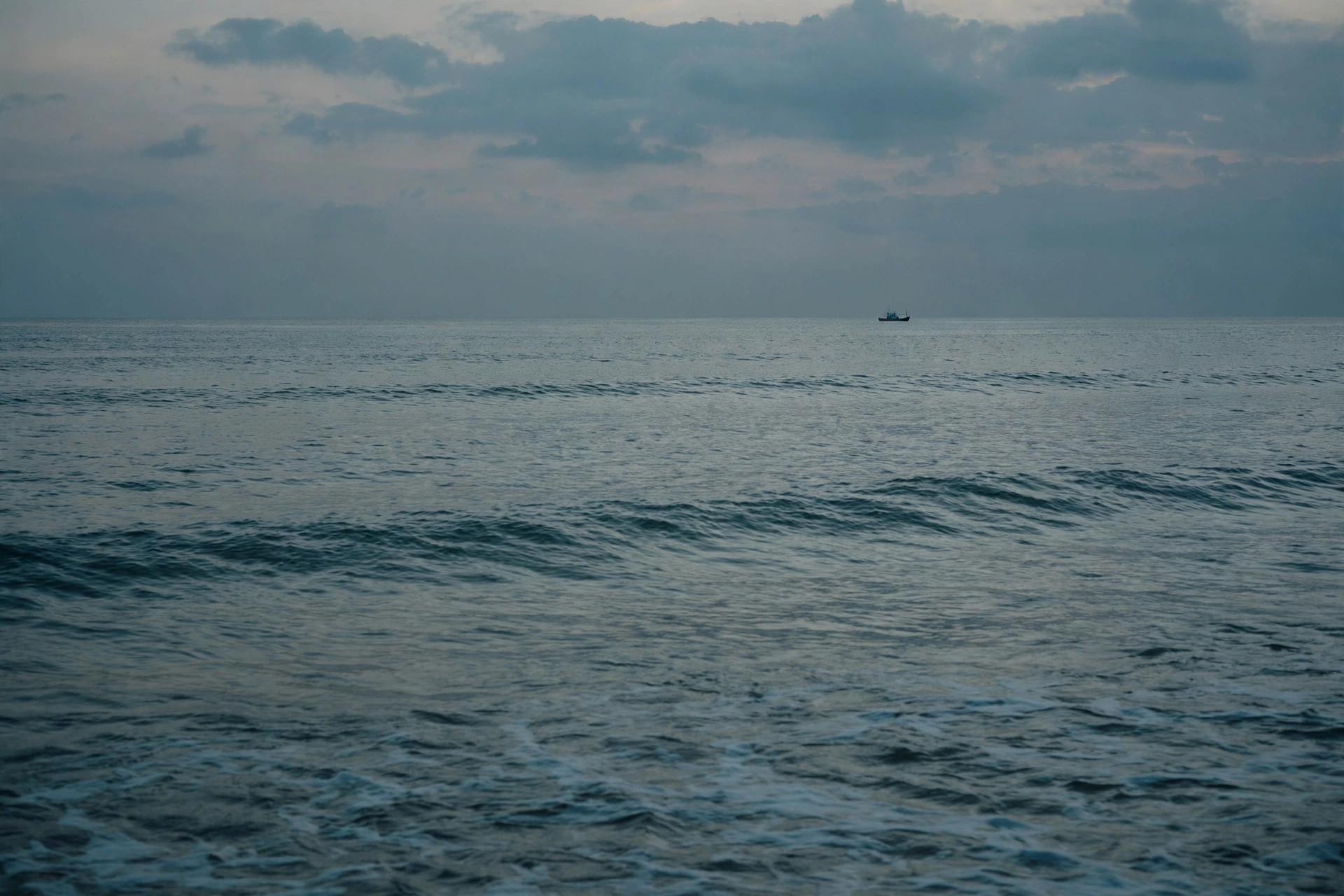 How much does burial at sea cost? A small charter boat on a calm, muted ocean under an overcast sky